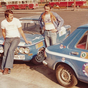Two men with blue rally cars carrying race decals