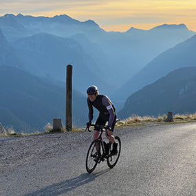 A road cyclist climbs a mountain road at sunset