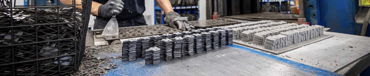 Sinter factory worker handling brake pad backing plates and compound materials