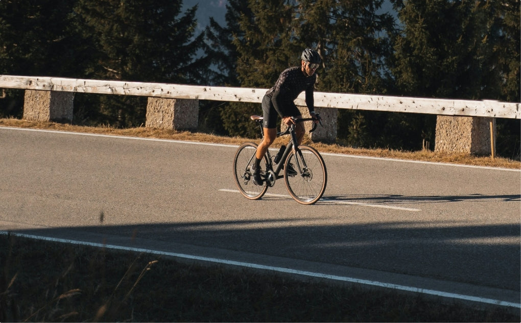 Mountain biker riding through autumn forest trail with fallen leaves