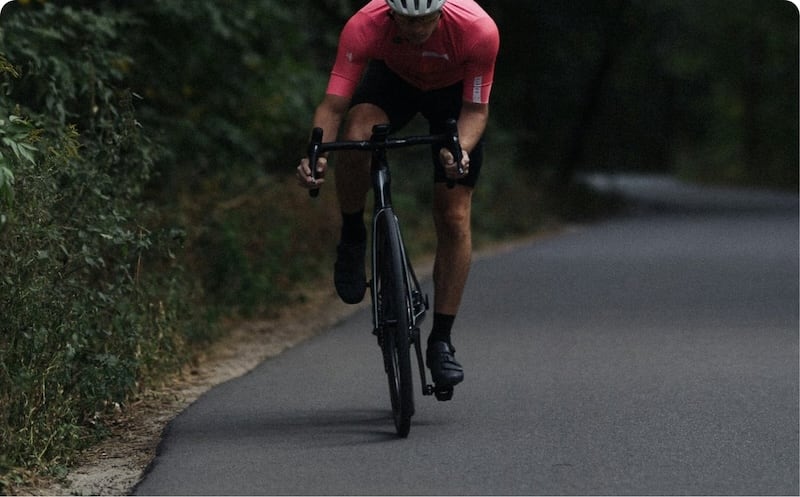 Road cyclist in pink jersey riding on scenic country road
